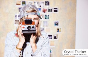 Nostalgia (the impact of memories on our lives) Young woman in front of a photo wall and taking pictures with a nostalgic camera