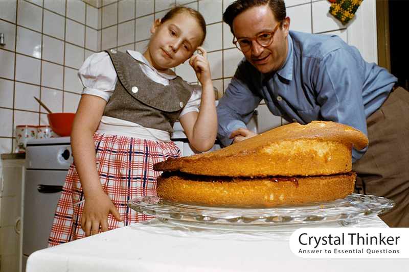Father and daughter in the kitchen in front of a deformed cake